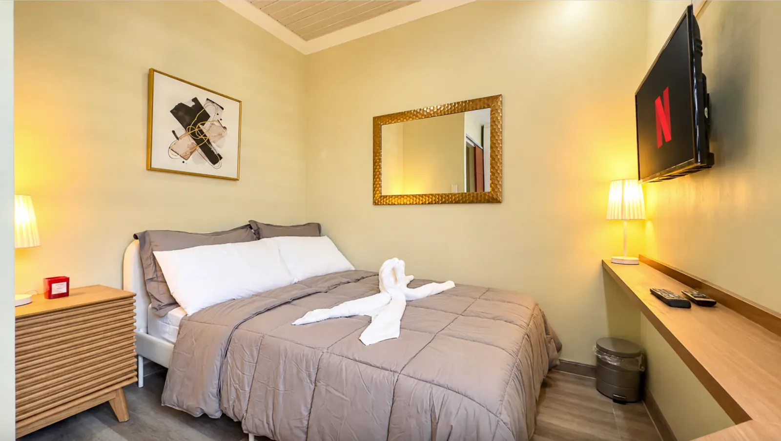 Bedroom with double bed, gold mirror and wall-mounted TV